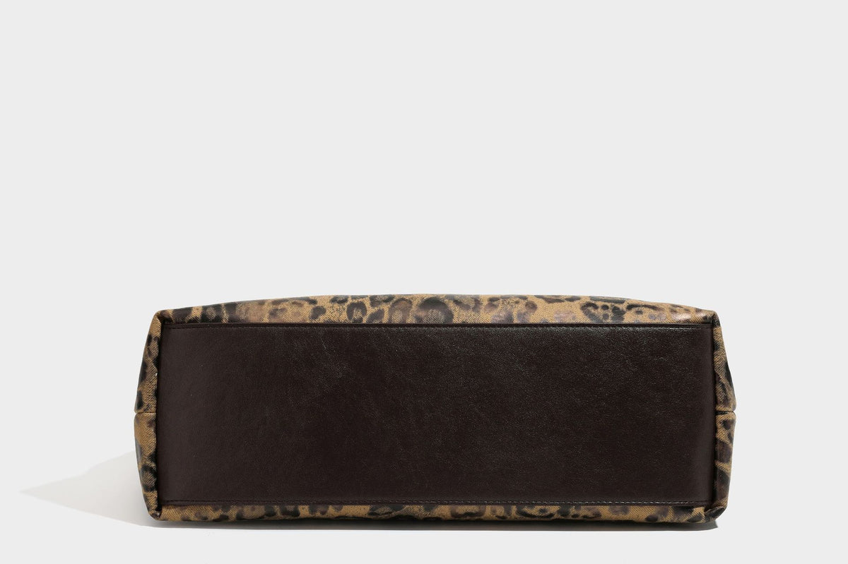 Slouchy leopard print hobo shoulder bag with glossy coated finish, top zipper closure, dark brown trim, and dangling charm