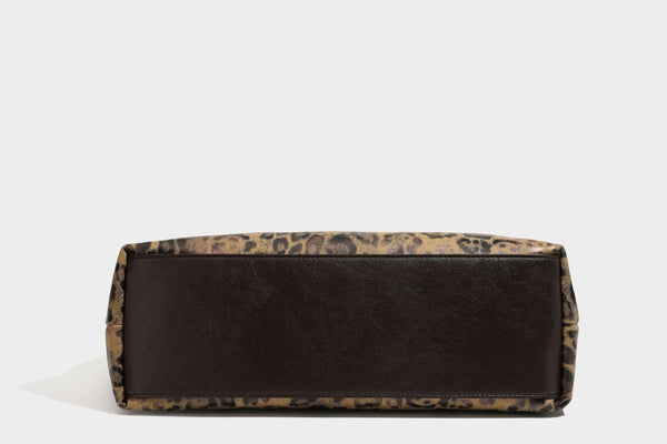 Slouchy leopard print hobo shoulder bag with glossy coated finish, top zipper closure, dark brown trim, and dangling charm