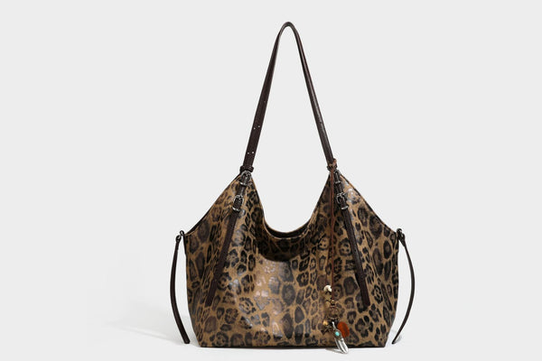 Slouchy leopard-print shoulder tote bag in tan and brown with long double straps, side tie straps, and dangling charm, detail