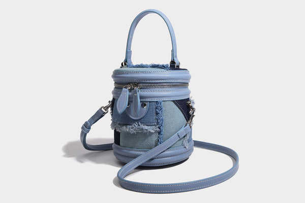 Mini cylindrical barrel bucket bag in denim patchwork with frayed edges, smooth leather-look trim, zip-around top closure