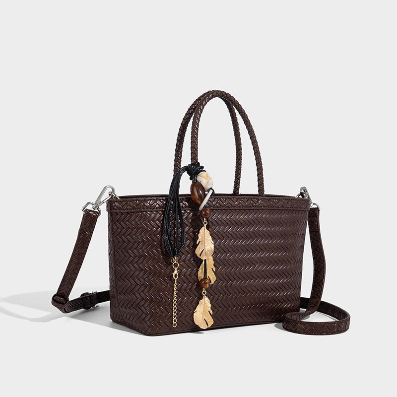 Structured chevron woven leather-look tote bag with braided top handles, gold feather charm, and adjustable shoulder strap