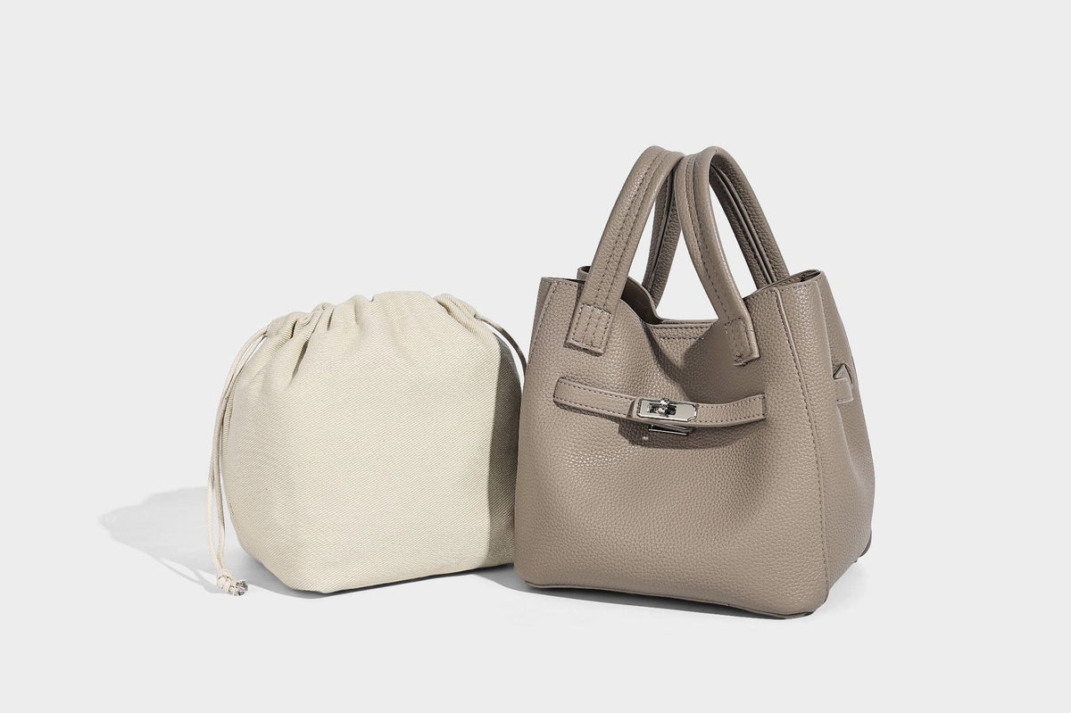Small structured pebbled bucket tote bag with dual top handles, silver turn-lock front pocket, and detachable shoulder strap