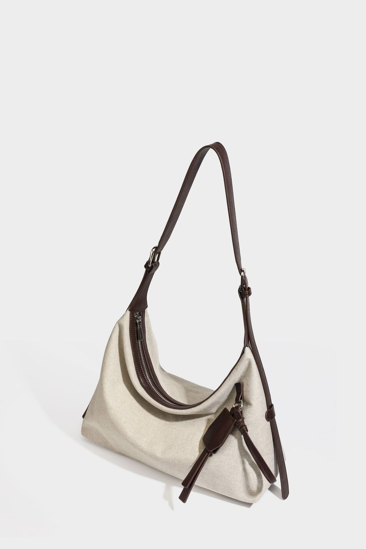 Lässige Hobo-Schultertasche aus haferfarbenem Canvas mit dunkelbraunen Besätzen in Lederoptik, silberfarbenem Reißverschluss und langem, verstellbarem