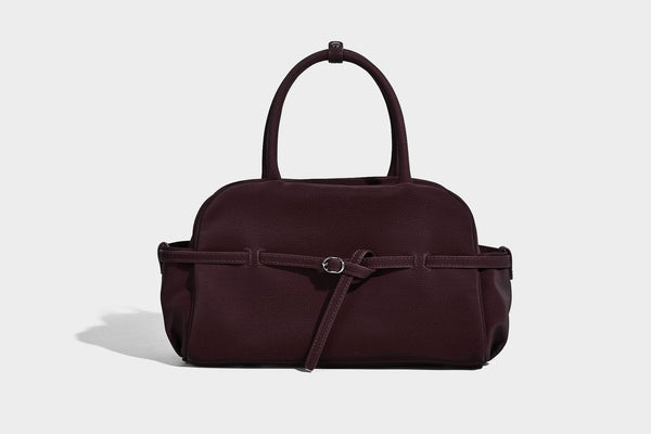 Strukturierte Henkeltasche aus mattem, genarbtem Material mit umlaufendem Riemen und Ringbeschlägen, zwei oberen Tragegriffen und abnehmbarem Crossbody-Riemen
