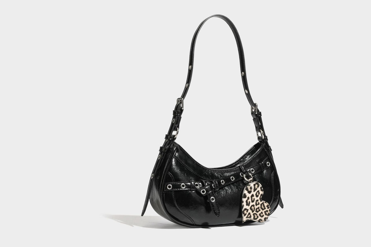 Kompakte, sichelförmige Schultertasche in glänzender bordeauxroter Lederoptik mit silberfarbenem Ösenschnallenriemen und Leopardenmuster