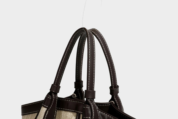 Cremefarbene geflochtene Tote-Bag mit dunkelbraunen Besätzen in Lederoptik, kontrastierenden weißen Nähten, zwei oberen Henkeln und abnehmbarem Schulter