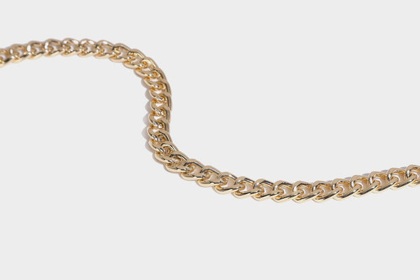Formstabile rechteckige Umhängetasche mit Überschlag, goldfarbenen Schmetterlingsanhängern und Perlenstrang-Verzierung an einer goldfarbenen Kette