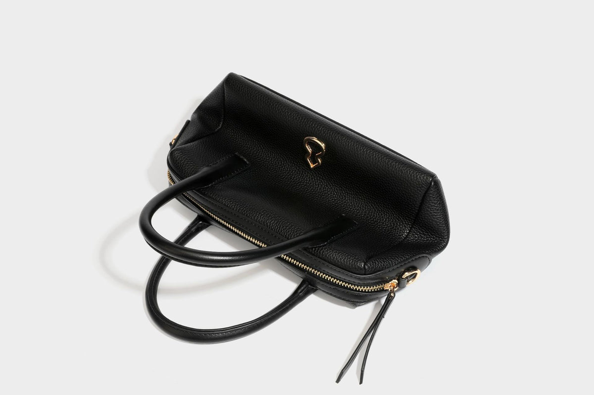 Small structured pillow satchel bag with pebbled leather-look finish, dual rolled top handles, gold-tone gourd emblem, and
