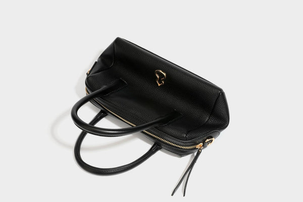 Small structured pillow satchel bag with pebbled leather-look finish, dual rolled top handles, gold-tone gourd emblem, and