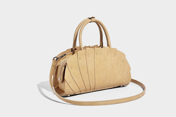 Structured dome satchel with fan-pleated leather-look exterior, dual top handles, and detachable shoulder strap, detail view