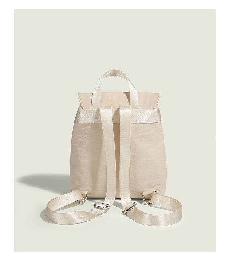 Soft matte nylon drawstring backpack with ruched bow-detail front zip pockets, top carry handle, and silver-tone hardware