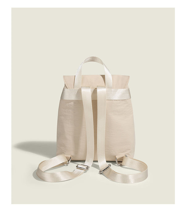 Soft matte nylon drawstring backpack with ruched bow-detail front zip pockets, top carry handle, and silver-tone hardware