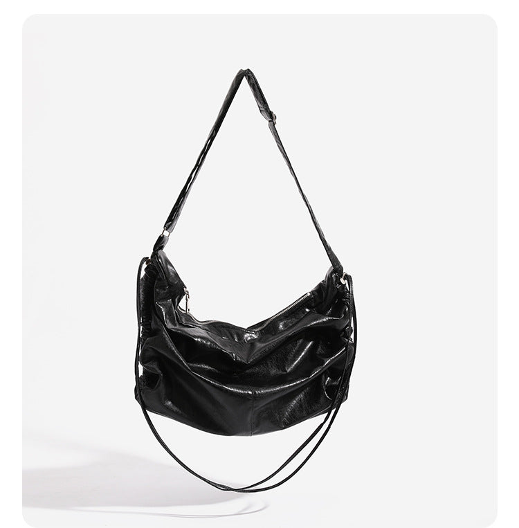 Oversized slouchy hobo shoulder bag with glossy crinkled leather-look finish, drawstring gathered sides, and silver-tone