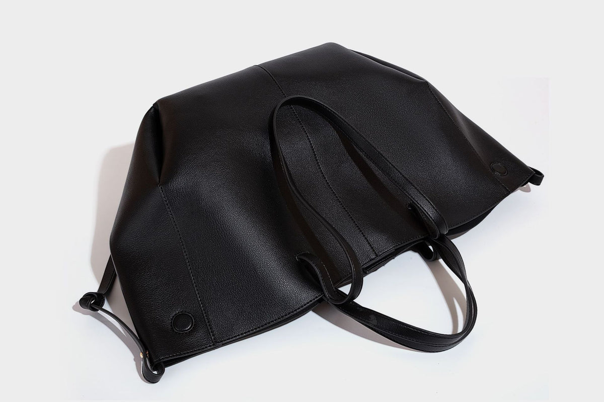 Große, formstabile trapezförmige Tote-Bag aus braunem Lederimitat mit genarbter Oberfläche, zwei Tragegriffen und seitlichen Bindebändern, Detail