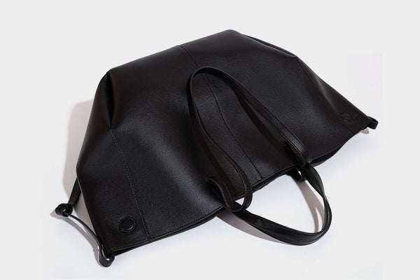 Große, formstabile trapezförmige Tote-Bag aus braunem Lederimitat mit genarbter Oberfläche, zwei Tragegriffen und seitlichen Bindebändern, Detail