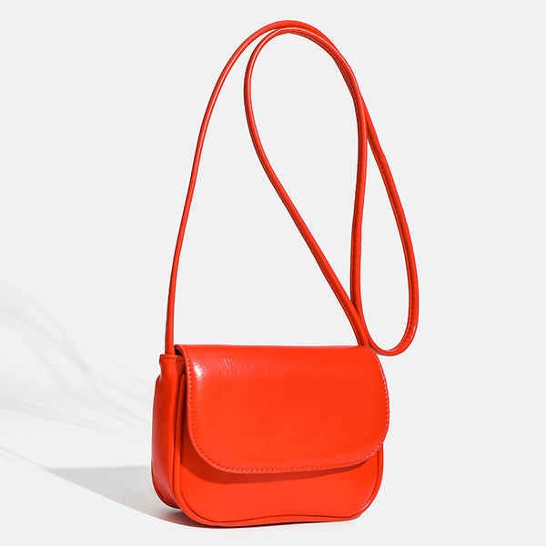 Compact rounded rectangular flap crossbody bag with glossy leather-look finish and long shoulder strap, detail view 3