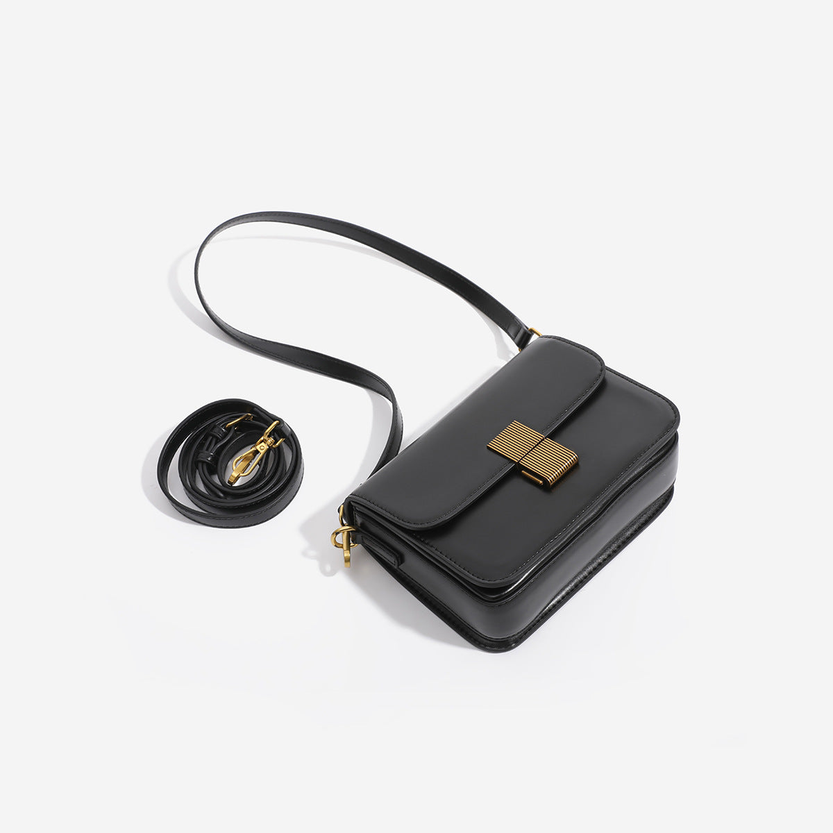 Mini structured black flap crossbody bag with gold-tone ribbed rectangular clasp and adjustable shoulder strap, detail view 4