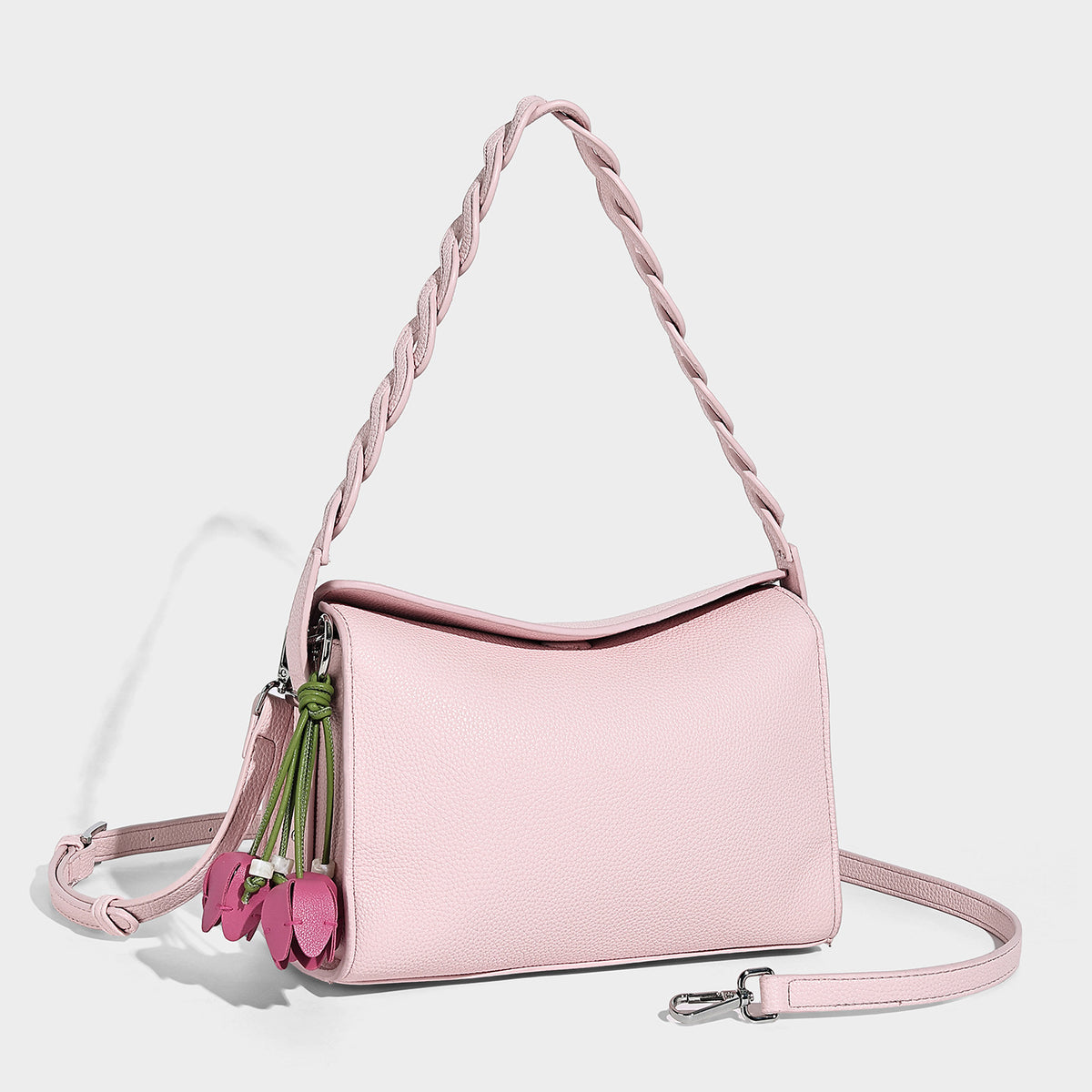 Small structured pebbled-finish shoulder bag with braided top handle, detachable crossbody strap, floral tassel charm, and