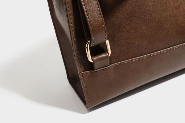 Structured suede-look convertible backpack handbag with flap closure and gold-tone emblem hardware in chocolate brown, detail