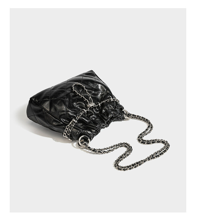 Glossy diamond-quilted drawstring bucket bag with silver chain shoulder strap and medallion charm, detail view 13