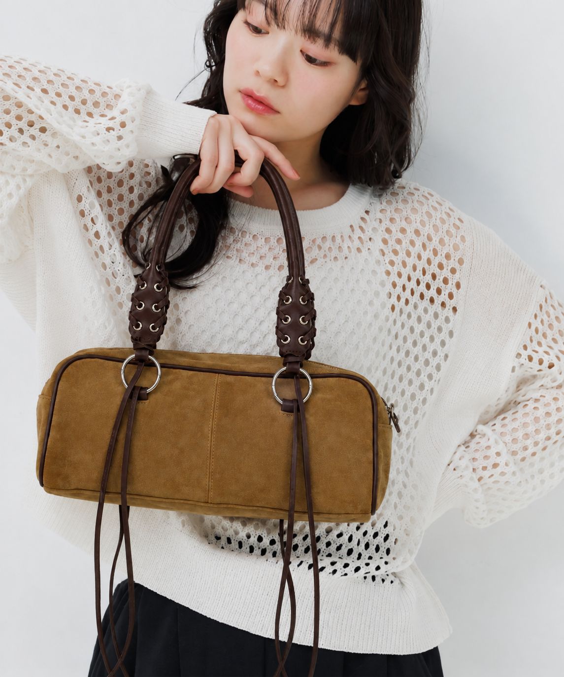 Rectangular suede-look barrel bag with laced eyelet handles, silver O-ring hardware, and hanging leather-look fringe tie