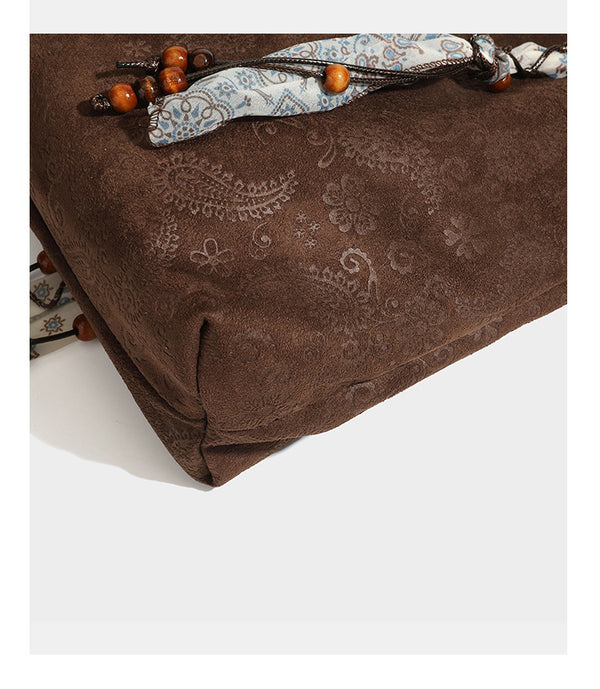 Slouchy paisley-embossed suede-look shoulder tote bag with braided patterned fabric straps and wood bead accents, detail view