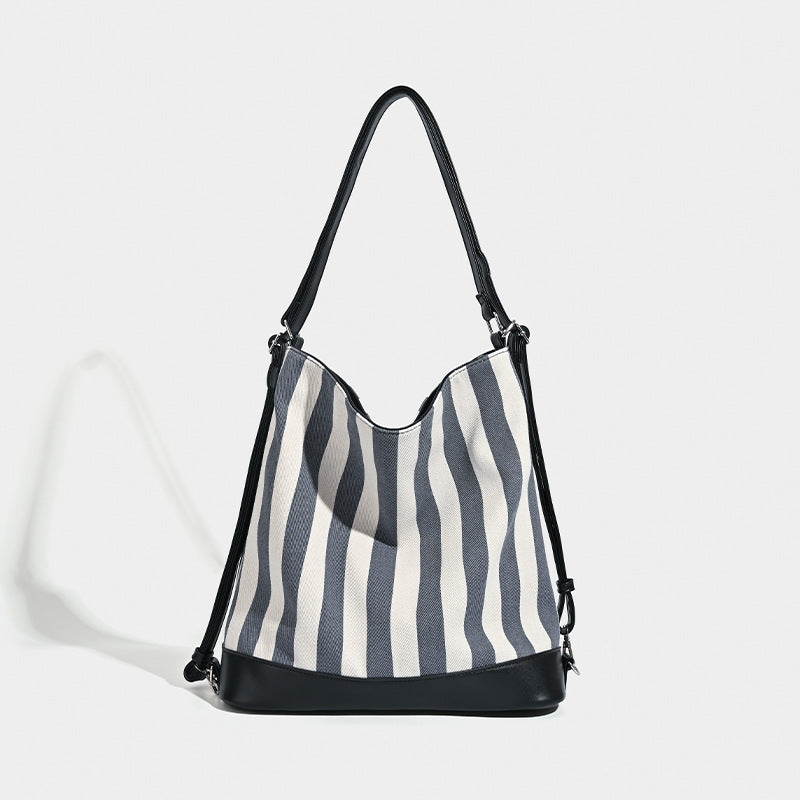 Wandelbarer Tote-Rucksack aus Canvas mit blau-weißen vertikalen Streifen, lederähnlichen Besätzen und silberfarbenen Metalldetails, Detailansicht