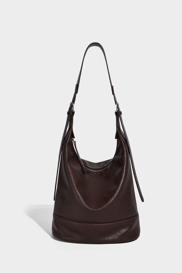 Slouchy bucket hobo shoulder bag in dark brown with glossy leather-look finish, top zip closure, and long adjustable, detail