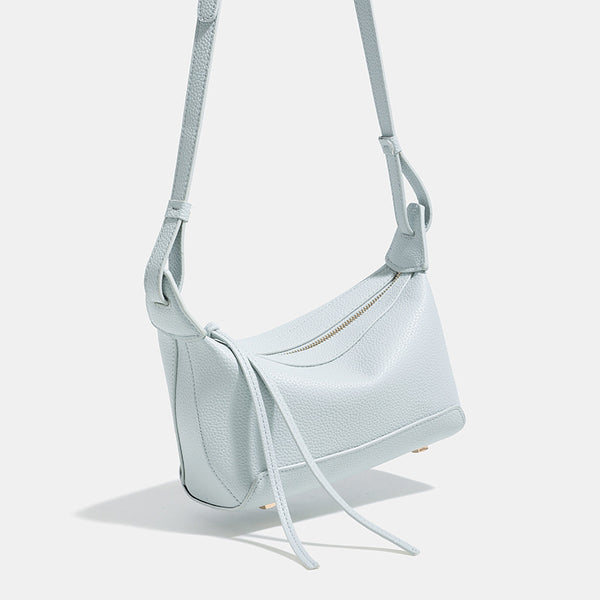 Small structured mini crossbody shoulder bag with pebbled texture, knotted adjustable strap, top zip closure, and gold-tone