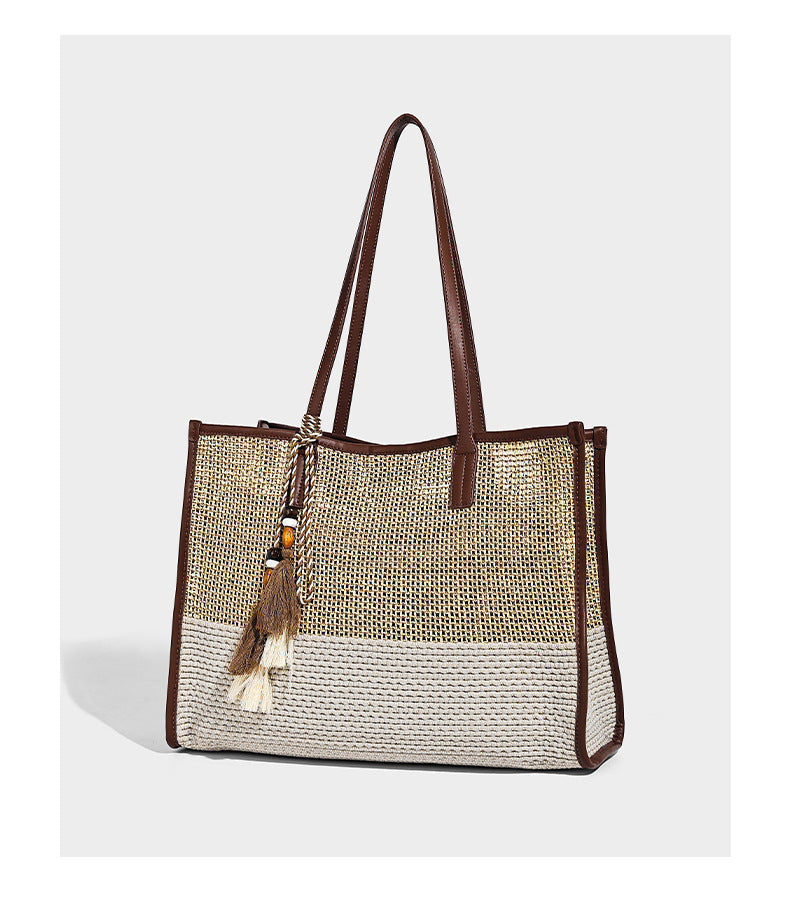 Two-tone woven straw tote bag with leather-look brown trim, long shoulder straps, and knotted tassel charm, detail view 10