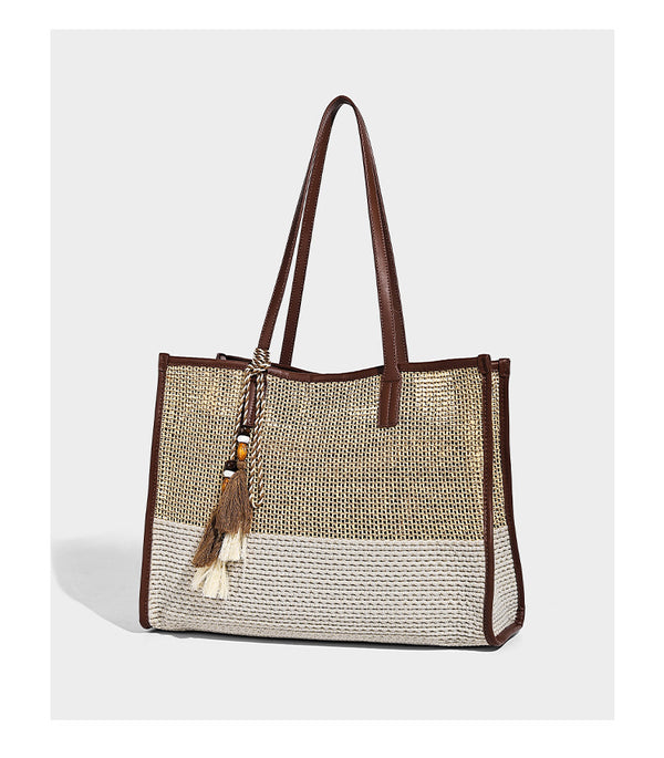Two-tone woven straw tote bag with leather-look brown trim, long shoulder straps, and knotted tassel charm, detail view 10