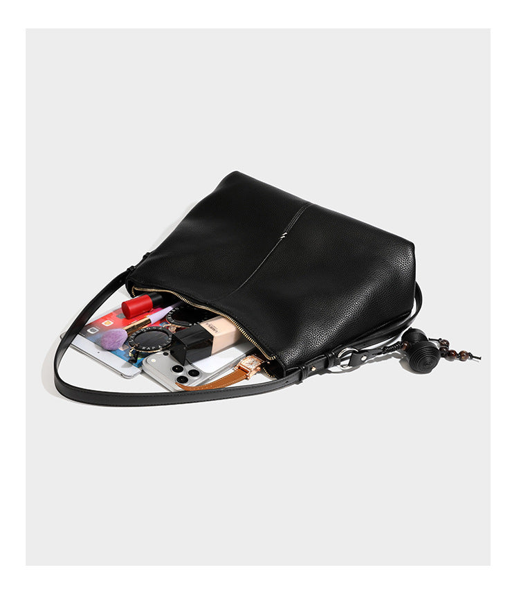 Slouchy hobo shoulder bag with pebbled leather-look finish, zip-top closure, gold-tone hardware, and hanging bead charm