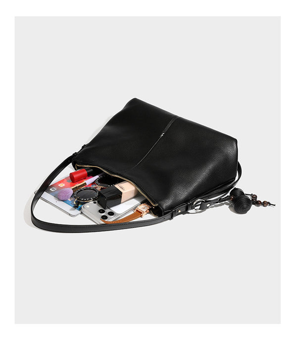 Slouchy hobo shoulder bag with pebbled leather-look finish, zip-top closure, gold-tone hardware, and hanging bead charm