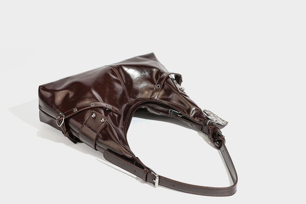 Glänzende dunkelbraune, lässig geschnittene Hobo-Schultertasche mit Riemendetail mit silberfarbenen Ösen, Reißverschlussfach auf der Vorderseite und Herz mit Leopardenmuster