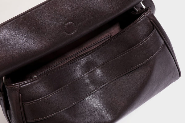 Formstabile rechteckige Schultertasche in Dunkelbraun mit Lederoptik, Überschlag und mehrlagigem Frontdetail sowie langem verstellbarem Riemen, Detail