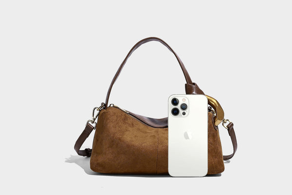 Kompakte Boston-Schultertasche in warmem Braun in Wildlederoptik mit glattem dunkelbraunem Besatz, übergroßen goldfarbenen Ringelementen und Reißverschluss oben