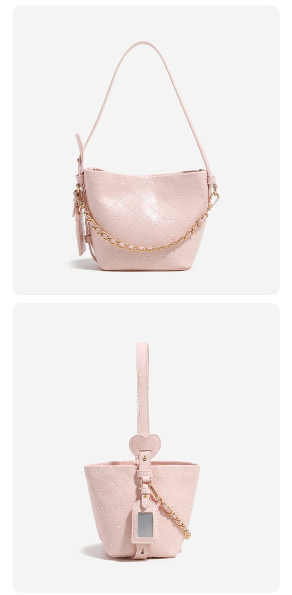 Small diamond-quilted bucket bag with gold-tone chain accent, heart strap detail, hanging tag, and matching zip coin pouch
