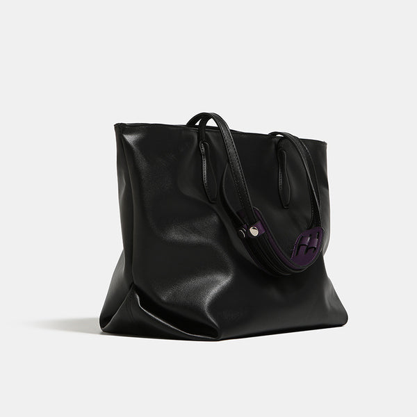 Large black leather-look trapezoid tote bag with double shoulder straps and purple accent hardware, detail view 3
