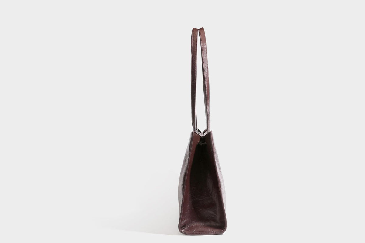 Strukturierte rechteckige Tote-Schultertasche aus glänzender, geknitterter Lederoptik mit langen Doppelträgern und Emblem in Goldoptik