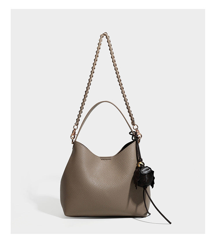 Schultertasche in genarbter Lederoptik im Hobo-Stil mit goldfarbener Kette, kurzem Tragegriff und dekorativem Anhänger an der Seite, Detailansicht