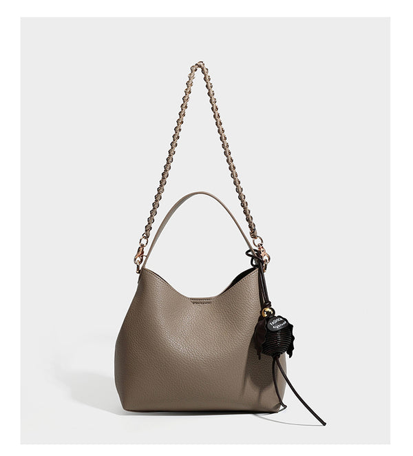 Schultertasche in genarbter Lederoptik im Hobo-Stil mit goldfarbener Kette, kurzem Tragegriff und dekorativem Anhänger an der Seite, Detailansicht