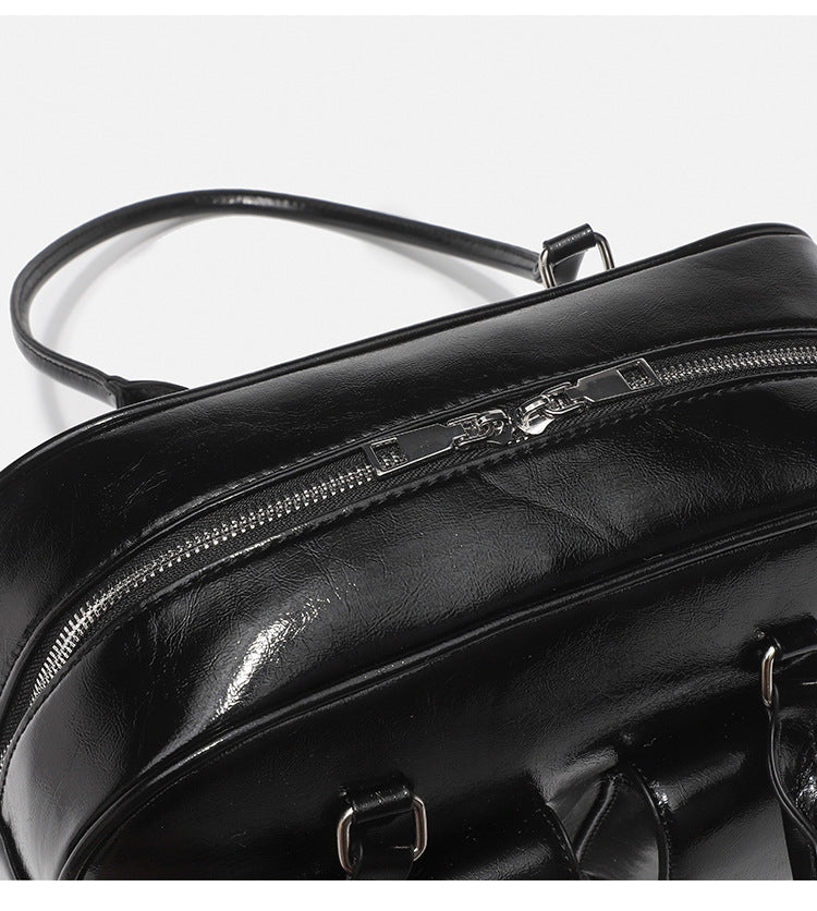 Structured glossy leather-look bowling shoulder bag with two front flap pockets, top zip closure, and long double shoulder