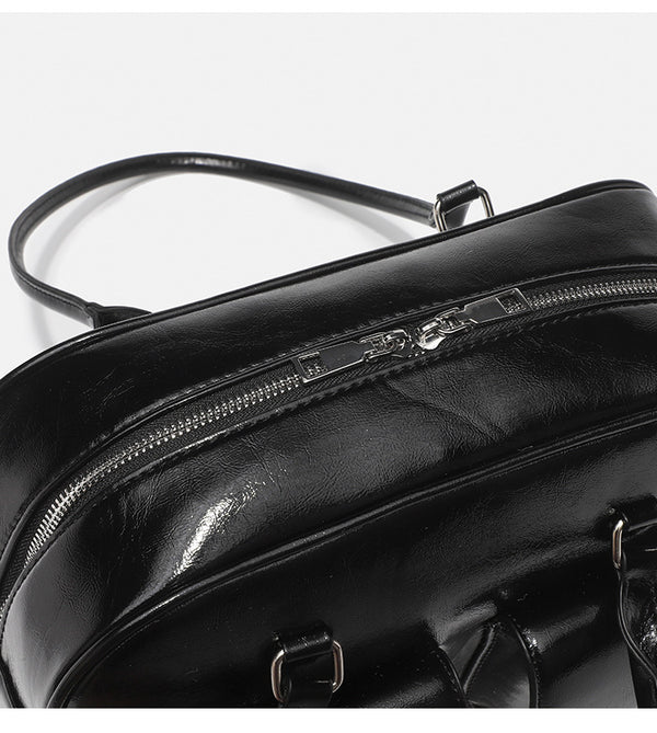Structured glossy leather-look bowling shoulder bag with two front flap pockets, top zip closure, and long double shoulder