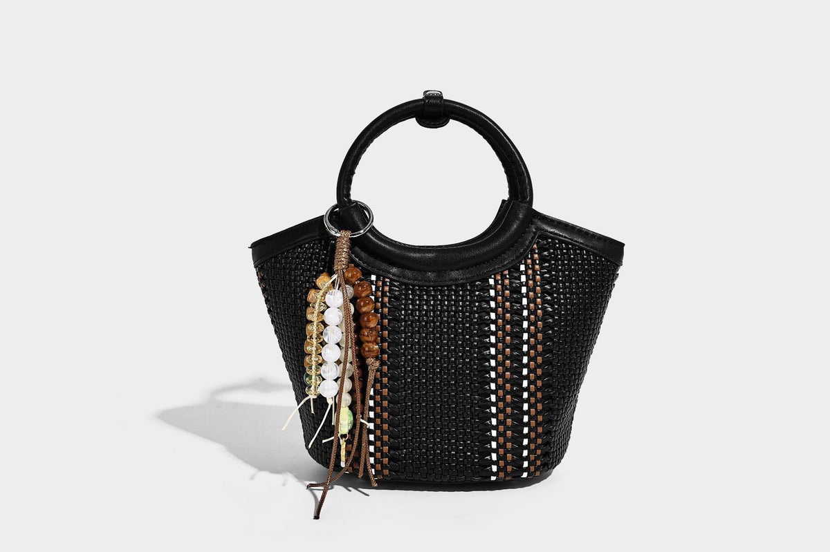 Kleine strukturierte Beuteltasche aus geflochtenem Material mit rundem Tragegriff in Lederoptik, silberfarbenen Beschlägen und perlenbesetztem Quastenanhänger, Detail