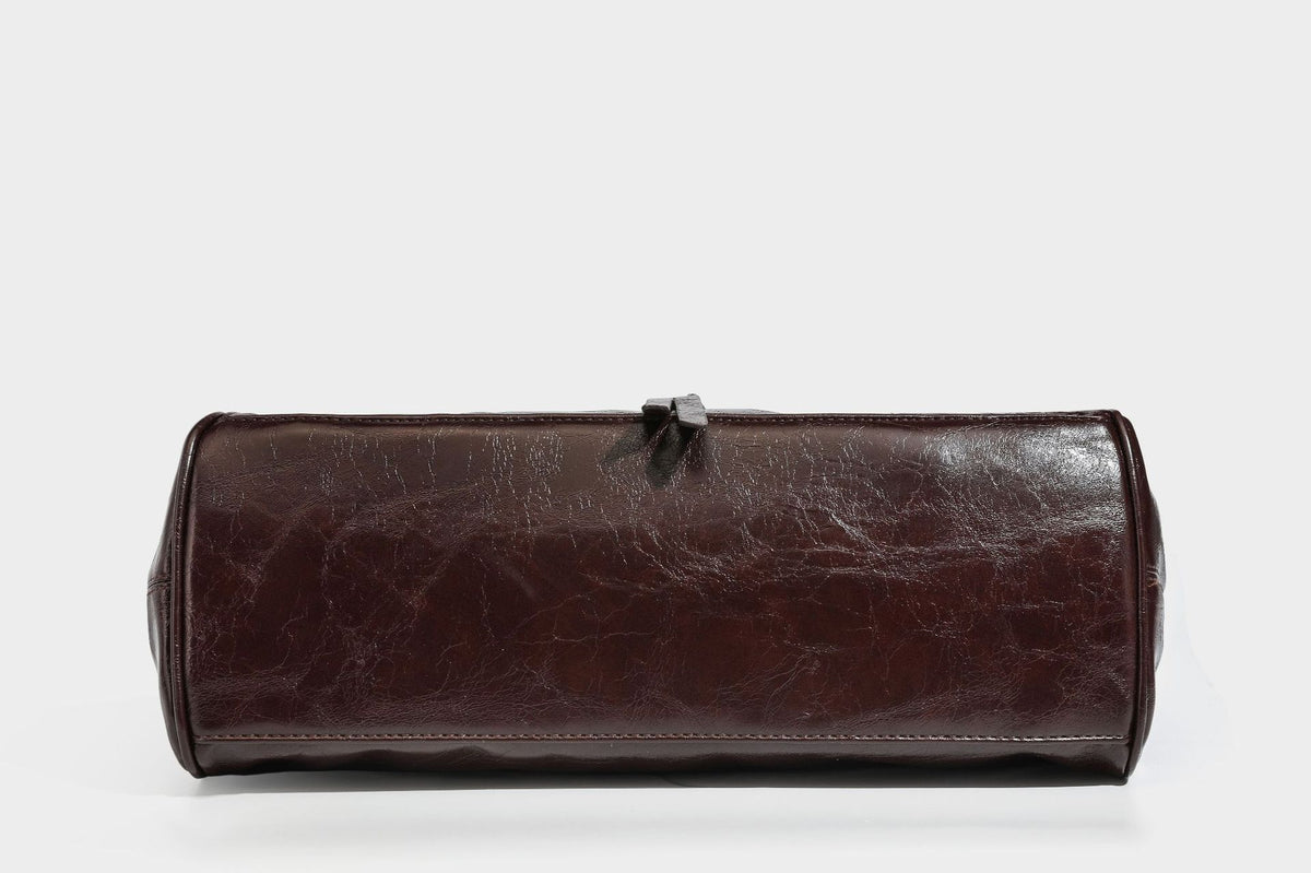 Glänzende Henkeltasche in Lederoptik mit zwei oberen Henkeln, goldfarbenen Nieten- und Ringbeschlägen, einem Riemendetail mit Schnalle auf der Vorderseite und