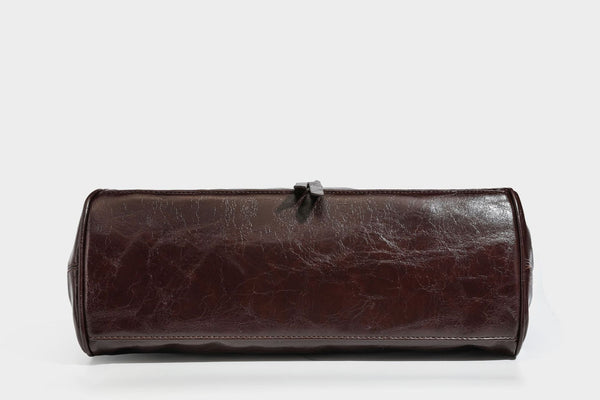 Glänzende Henkeltasche in Lederoptik mit zwei oberen Henkeln, goldfarbenen Nieten- und Ringbeschlägen, einem Riemendetail mit Schnalle auf der Vorderseite und