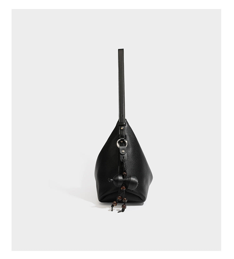 Slouchy hobo shoulder bag with pebbled leather-look finish, zip-top closure, gold-tone hardware, and hanging bead charm