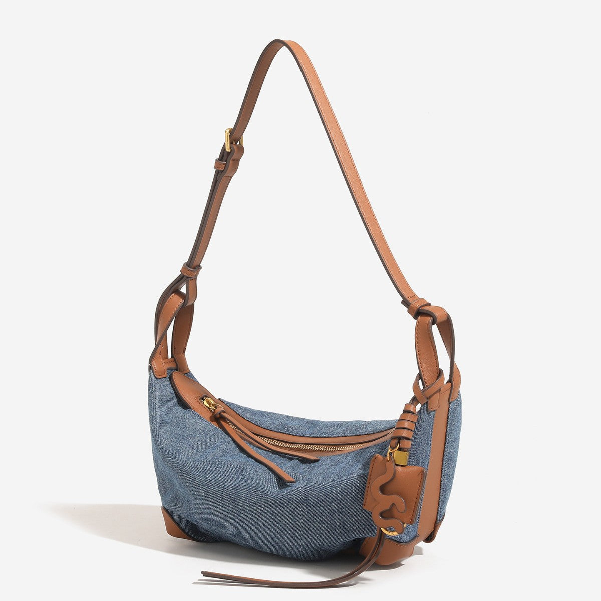Washed denim canvas crescent hobo bag with tan leather-look trim, knotted strap detail, and gold-tone zipper hardware, detail