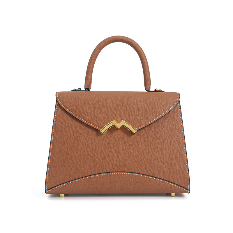 Structured trapezoid top-handle satchel in golden brown cross-grain textured finish with gold M-shaped clasp hardware and