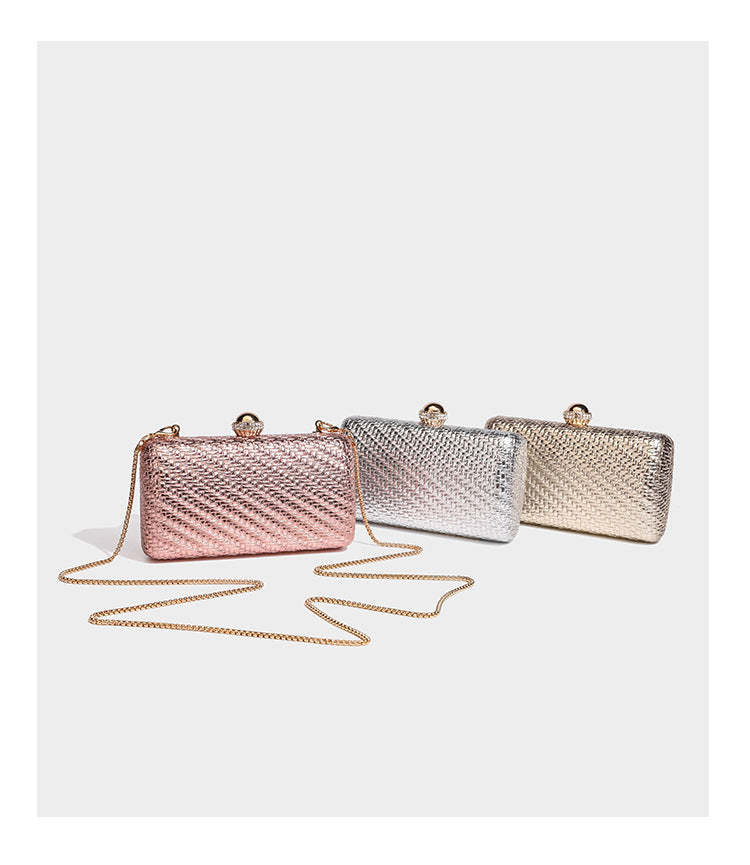 Small structured metallic woven-texture box clutch bag with jeweled kiss-lock dome clasp and slim gold chain strap, detail